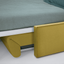 Ito queen wall bed with reclining sofa shown open as a bed, featuring olive green upholstery and built-in shelf in a modern white space.