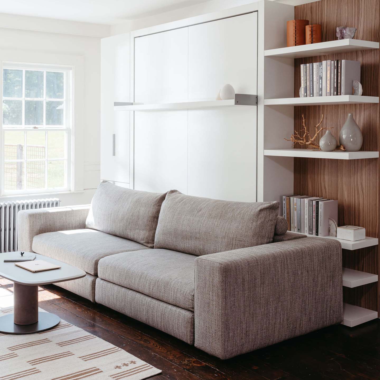 Contemporary living space featuring the Tango Sofa in front of a closed wall bed system, paired with minimalist shelving and modern natural light—perfect for compact, multifunctional interiors.